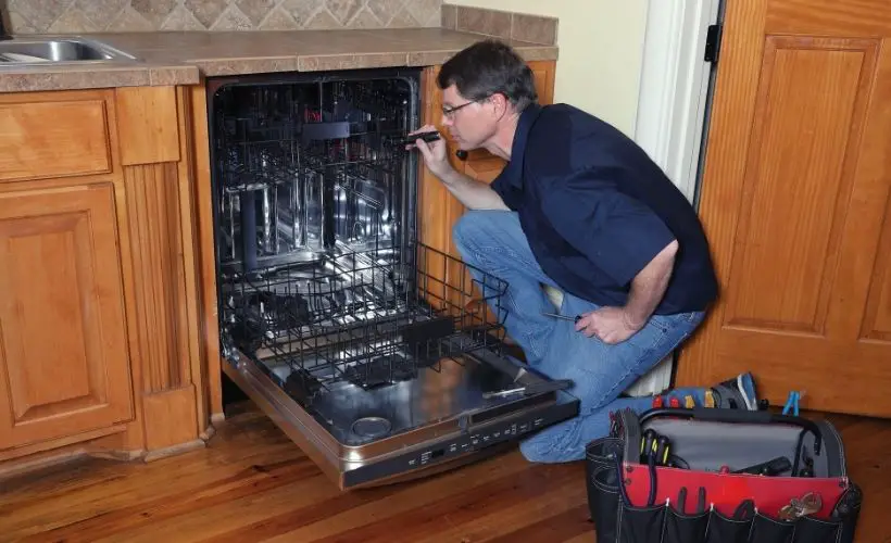 Appliance repairman works on broken dishwasher
