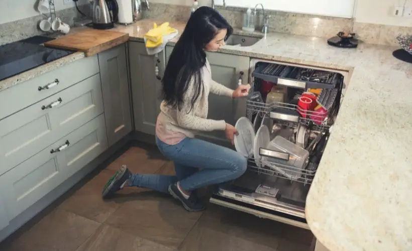 Woman arranging plates in dish washer